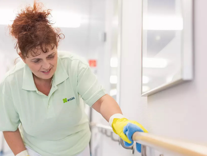 WISAG Mitarbeiterin beim Reinigen des Geländers in einem Krankenhausflur