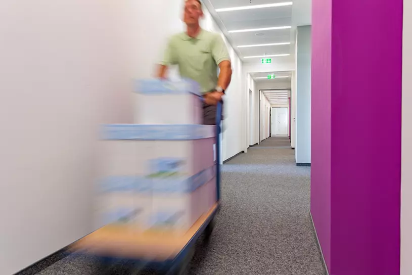 WISAG Mitarbeiter schiebt Pakete durch einen Flur
