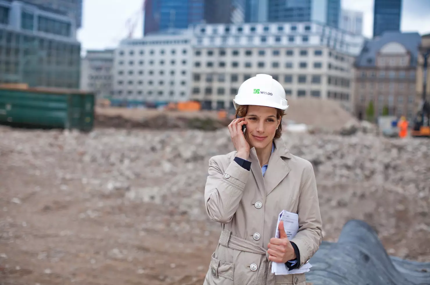 WISAG Mitarbeiterin telefoniert vor Baustelle