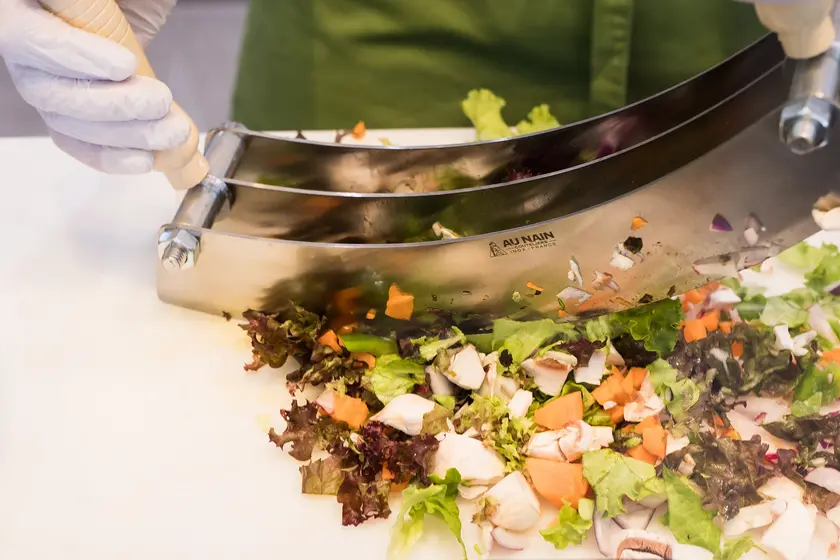 Detailaufnahme: Wiegemesser schneidet gemischten Salat
