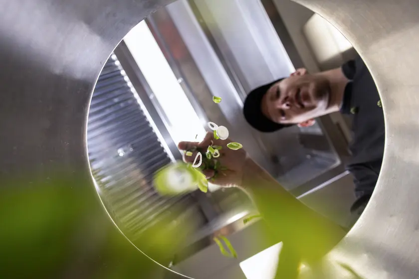 Koch wirft klein geschnittene Lauchzwiebeln in einen Topf