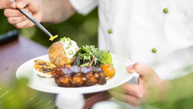 WISAG Mitarbeiter richtet einen Teller mit Essen an