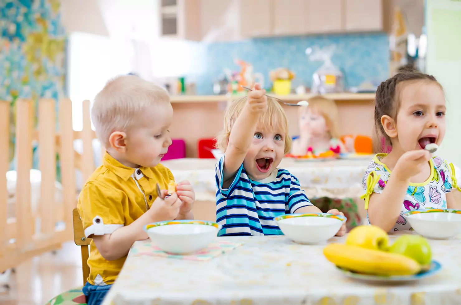 Drei Kinder sitzen am Tisch und essen mit Freude