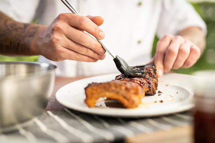 Ein Koch mariniert ein schönes Stück Steak auf einem Teller