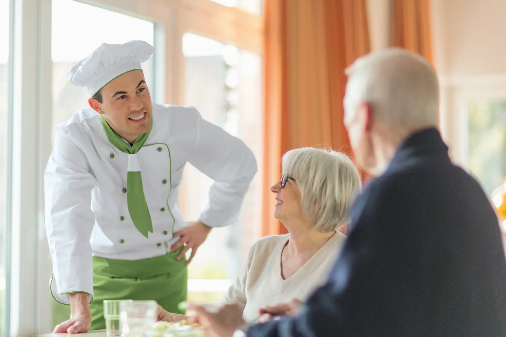 WISAG Koch im gespräch mit zwei älteren Menschen