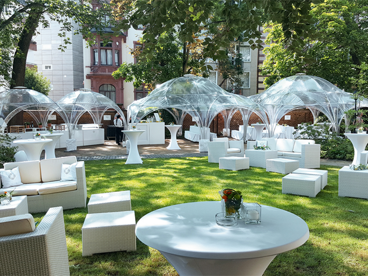 Veranstaltung im freien mit weißen Gartenmöbeln und durchsichtigen Kuppelzelten