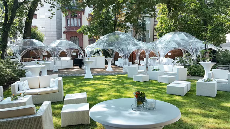 Veranstaltung im freien mit weißen Gartenmöbeln und durchsichtigen Kuppelzelten